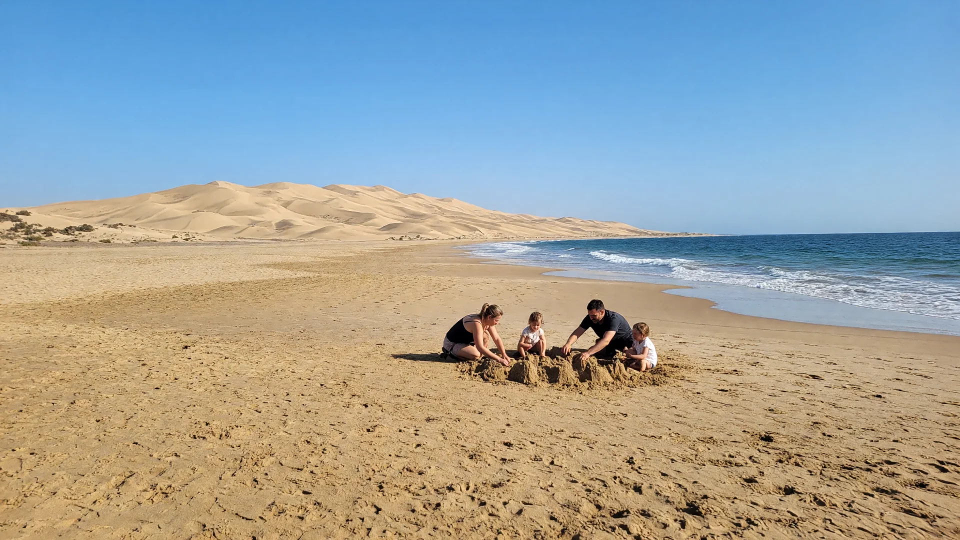 gezin met twee kinderen bouwt een zandkasteel op het strand van Maspalomas op Gran Canaria