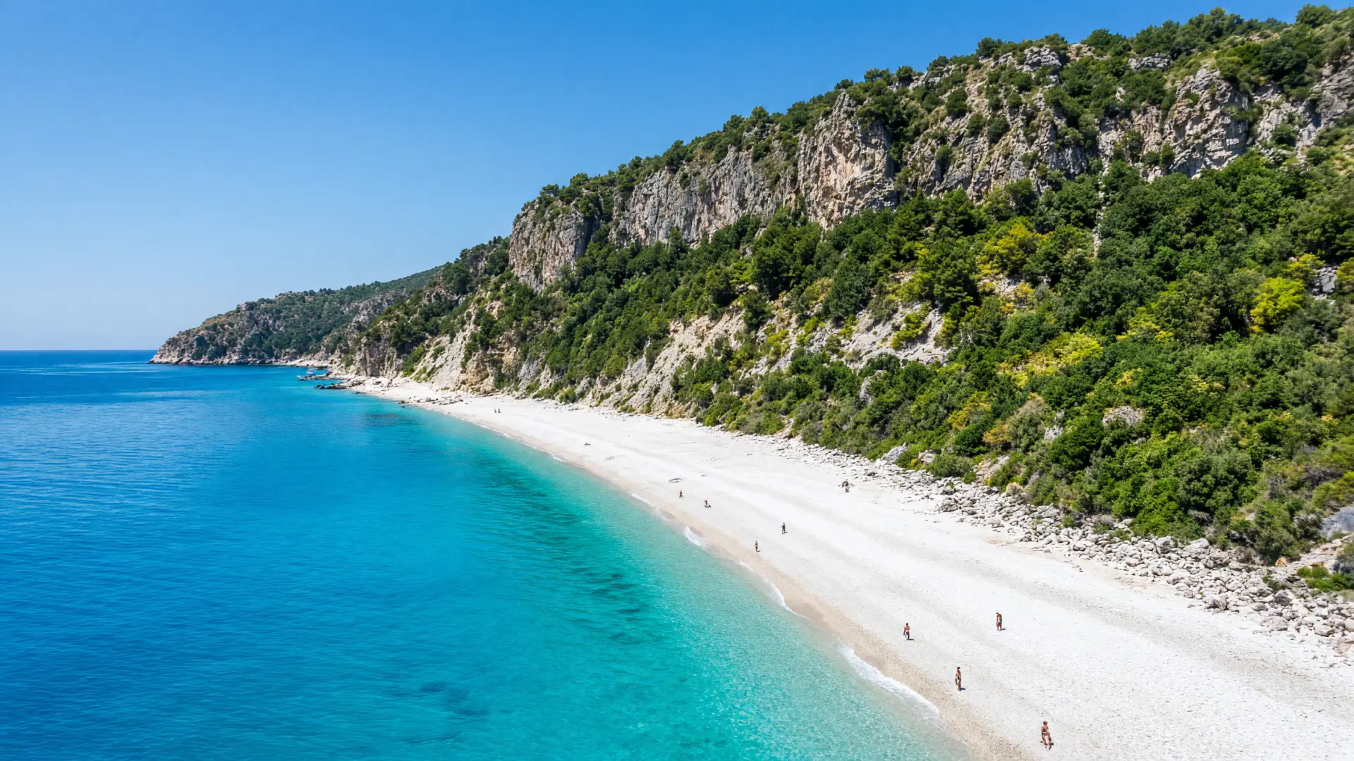 Wit kiezelstrand met turquoise water onder groene kliffen op Kefalonia