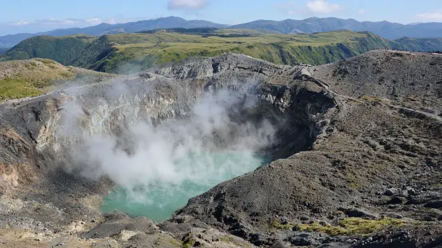 De rokende krater van de vulkaan Aso op Kyushu, met kleine wandelaars op de kraterrand