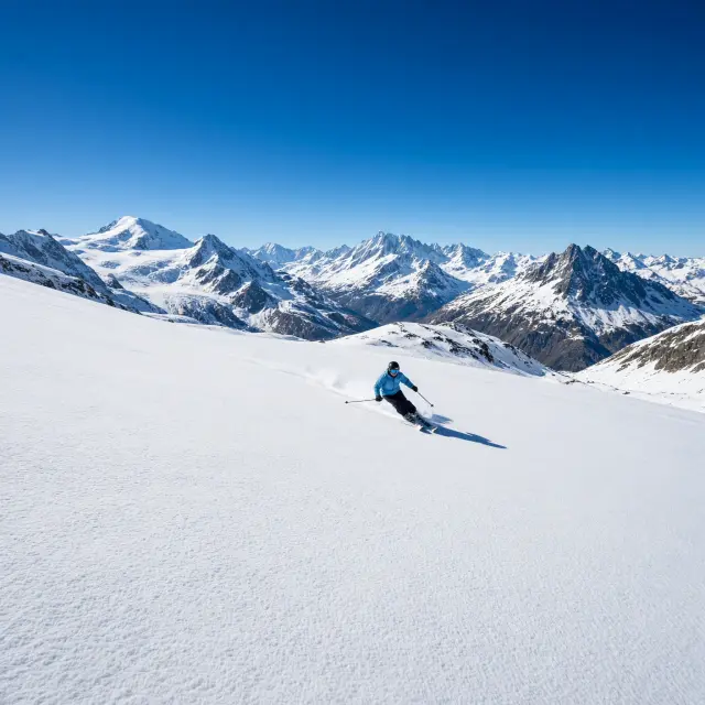 Skiërs dalen af op de besneeuwde gletsjerpistes van de Kitzsteinhorn boven Kaprun, met bergtoppen op de achtergrond