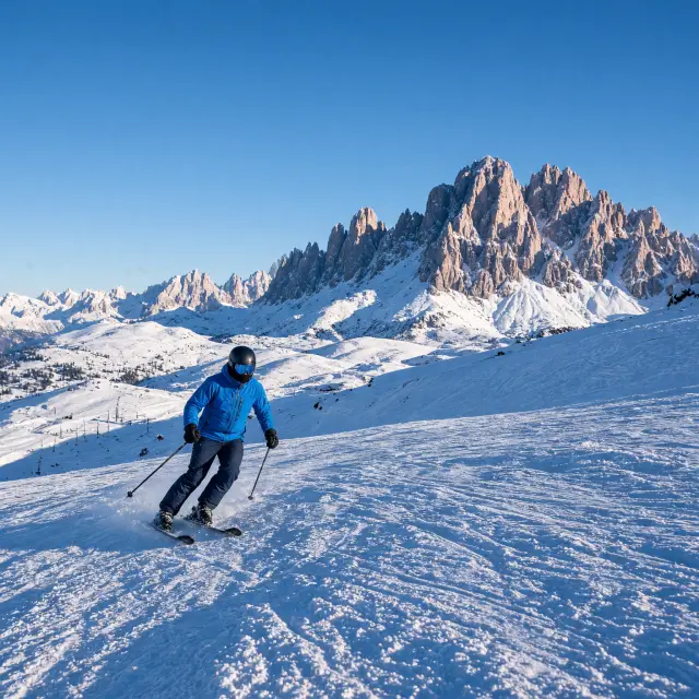 Brede zonnige skipiste op de Seiser Alm met skiërs en de rotswanden van de Schlern op de achtergrond