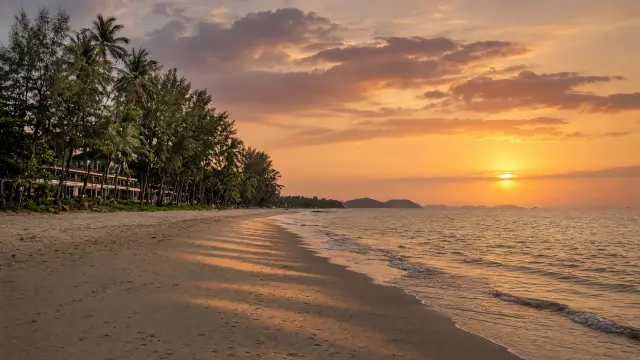 Lang, rustig zandstrand met palmbomen in Khao Lak bij zonsondergang