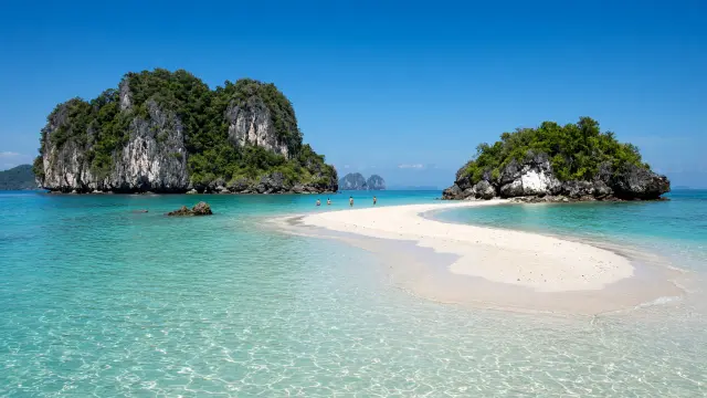 Zandbank tussen twee kalksteeneilandjes in ondiep turkoois water bij Krabi