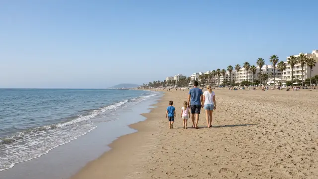 Gezin met twee kinderen wandelt in februari langs de zee op een breed zandstrand