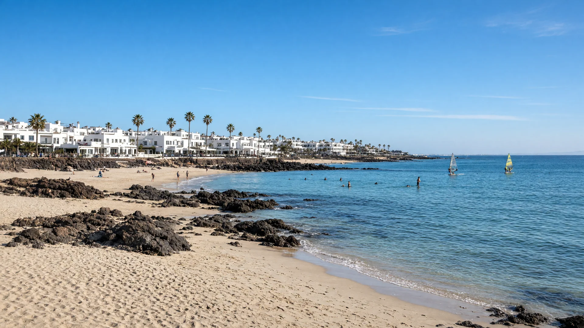 Strand met lavarotsen en witte vakantiegebouwen in Costa Teguise