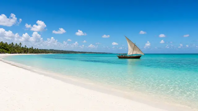 Wit strand en een dhow op helder water aan de noordkust van Zanzibar