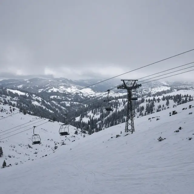 Skiërs dalen af op brede, zonnige pistes in het verbonden skidomein bij Le Corbier met bergtoppen op de achtergrond