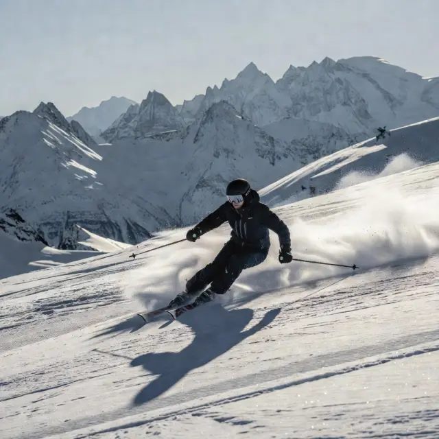 Skiërs op de steile hellingen van Arc 2000 met panoramisch uitzicht over de besneeuwde toppen van de Franse Alpen