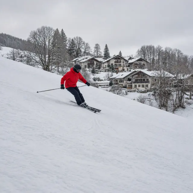 Les Coches dorpsplein met winkels, terrasjes en skiërs bij de gondel op een zonnige wintermiddag
