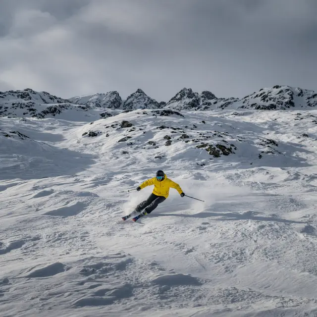 Skiërs op besneeuwde pistes in hooggelegen Frans skigebied onder heldere blauwe hemel in april