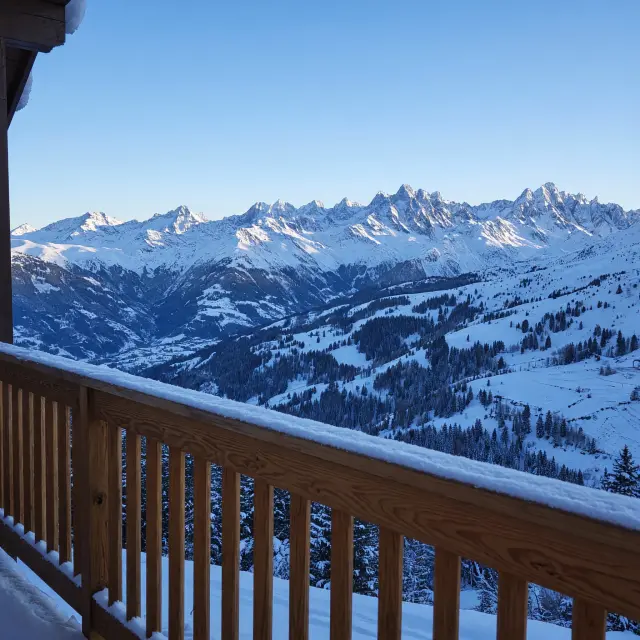 Rustige berghuizen met besneeuwde pistes en panoramisch uitzicht over de Alpen op een zonnige winterdag