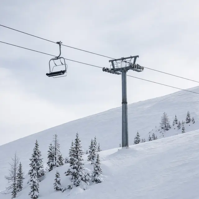Skiërs dalen af op brede, zonnige pistes met uitzicht op besneeuwde bergtoppen vlak bij Maria Alm