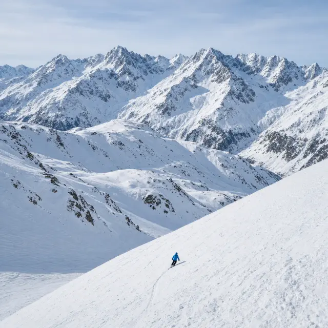 Skiërs op een brede, besneeuwde piste met uitzicht op de hoge toppen boven Val Thorens, vlak bij Méribel