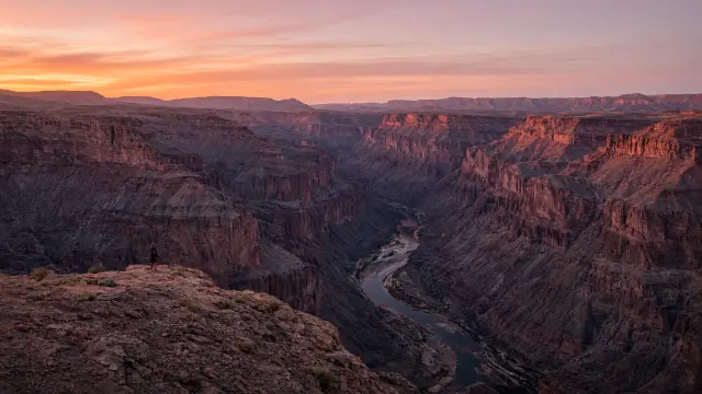 Fish River Canyon bij zonsondergang met een kleine wandelaar op de rand