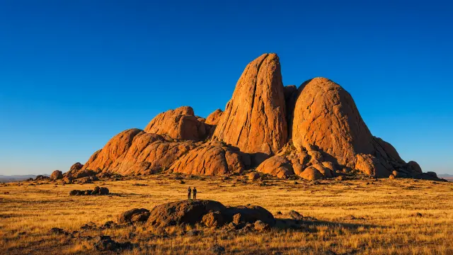 Granietkoepels van de Spitzkoppe in het avondlicht met twee kleine figuren op de rotsen