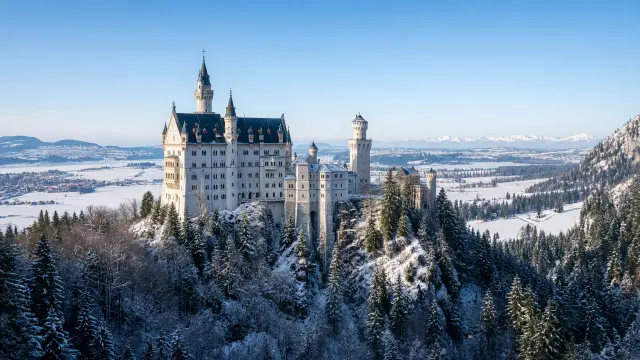 Kasteel Neuschwanstein op een rots tussen besneeuwde dennenbossen in Beieren