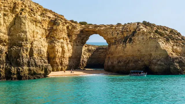 Zeegrot met een opening in het dak boven een zandstrandje aan de Algarve