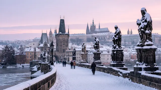 De Karelsbrug in Praag met besneeuwde beelden en de Praagse Burcht op de achtergrond