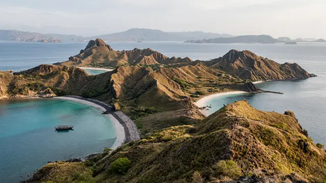 Uitzicht over de baaien van Padar in het nationaal park Komodo, met een bootje en wandelaars op het pad