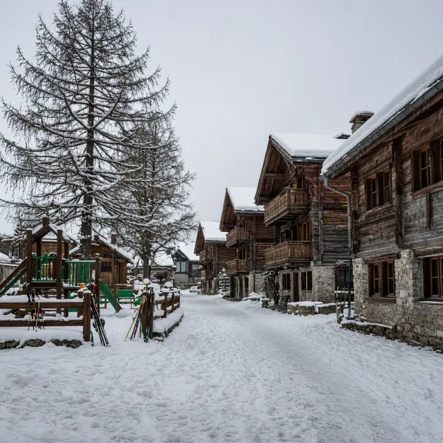 Autovrij bergdorp met traditionele chalets en moderne liften onder blauwe hemel op zonnig hoogplateau in de Oostenrijkse Alpen