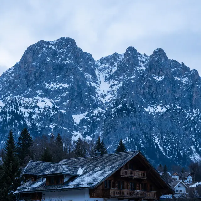 Pittoresk bergdorp Ellmau met traditionele Tiroler chalets en imposante Wilder Kaiser rotsformatie op de achtergrond onder heldere winterse hemel