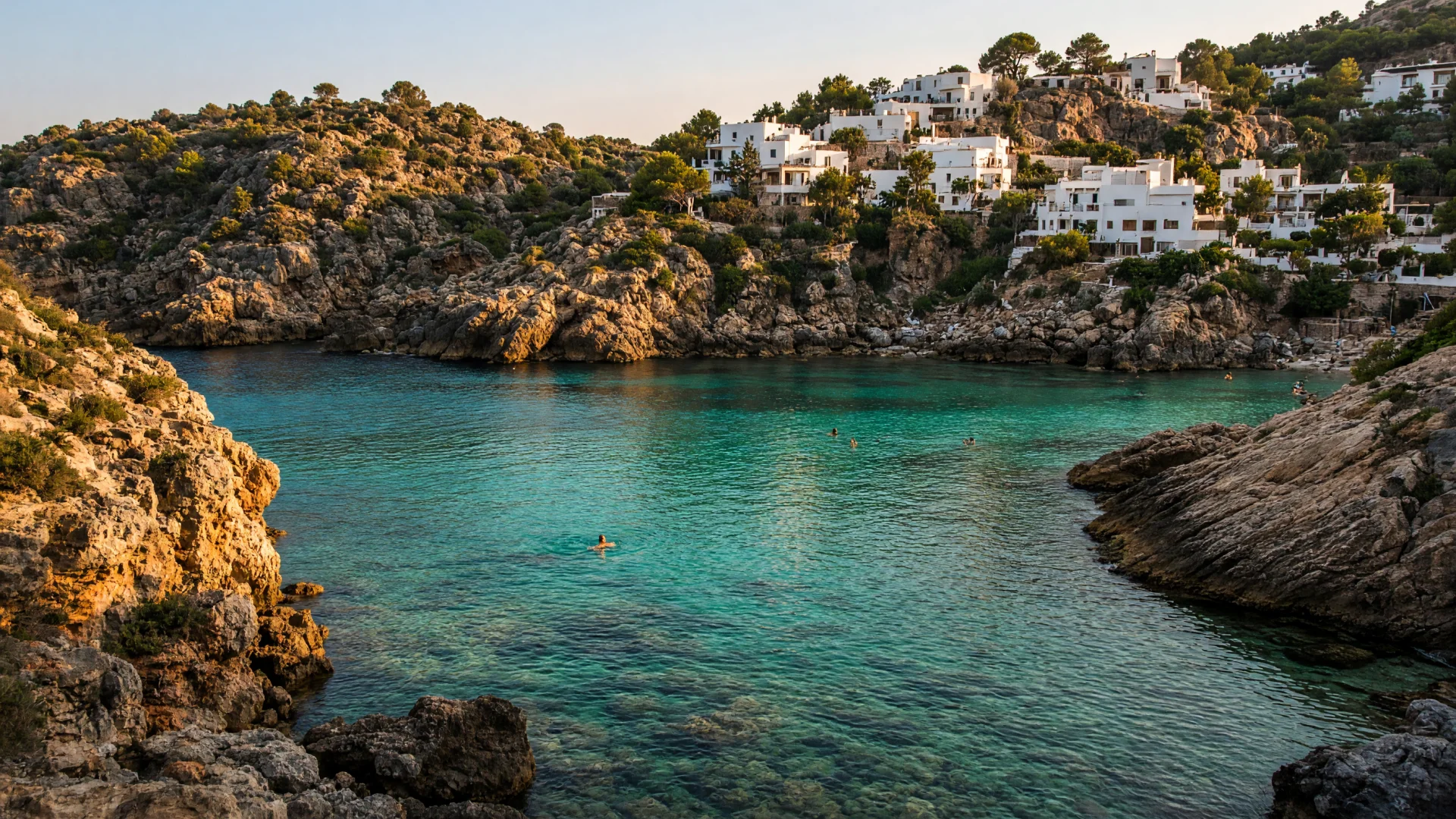 Rotsachtige baai met helder water en witte huizen op Ibiza
