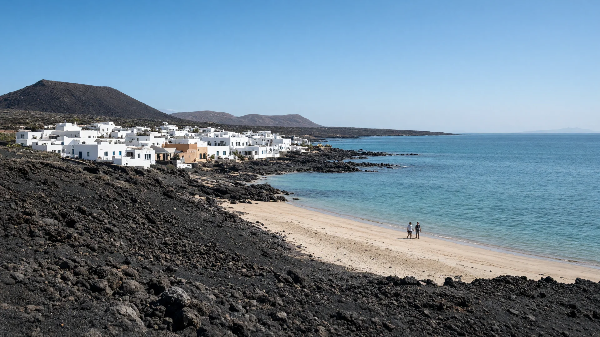 Vulkanisch landschap met wit dorpje en strand op Lanzarote