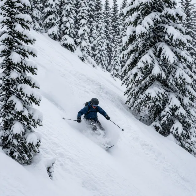 Skiër maakt verse sporen in diepe poedersneeuw op een steile, onbewerkte helling boven St. Anton am Arlberg