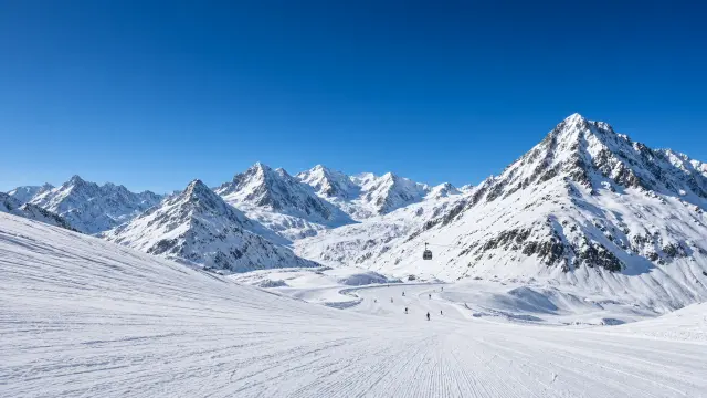 Brede gletsjerpistes op de Stubaier Gletscher met hoge bergtoppen en een gondel