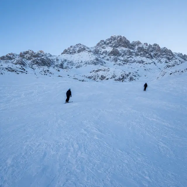Besneeuwde pistes en bergchalets in het Franse skistation SuperDévoluy onder een strakblauwe lucht