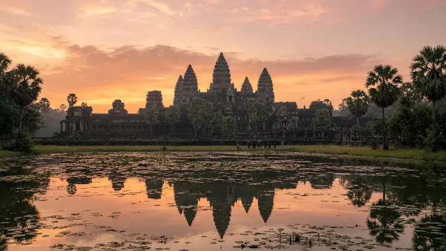 De torens van Angkor Wat bij zonsopgang, weerspiegeld in de vijver, met kleine bezoekers