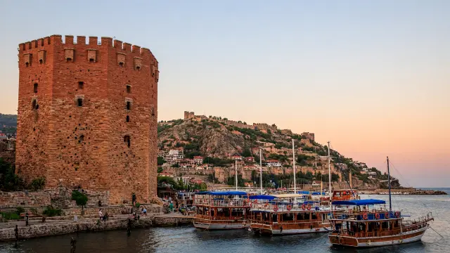 De achthoekige Rode Toren aan de haven van Alanya met excursieboten