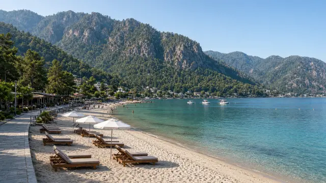 Strand van İçmeler bij Marmaris met ligbedden en steile beboste bergen erachter