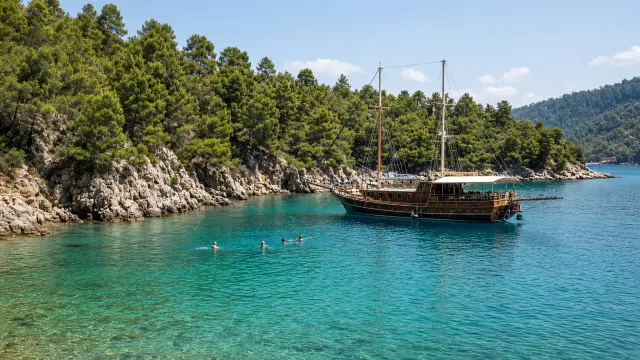 Houten gulet voor anker in een turquoise baai met pijnbomen bij Marmaris