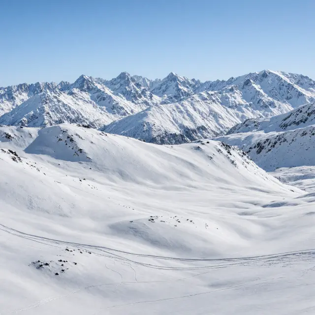 Skiërs op brede pistes met moderne liften en bergtoppen op de achtergrond in het hooggelegen skigebied