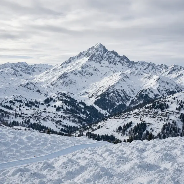 Besneeuwde bergpas met haarspeldbochten boven Valloire in de Franse Alpen onder een heldere blauwe winterhemel