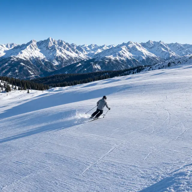 Moderne skiliften en perfect geprepareerde pistes in het Oostenrijkse berglandschap met uitzicht op besneeuwde drieduizenders van de Hohe Tauern
