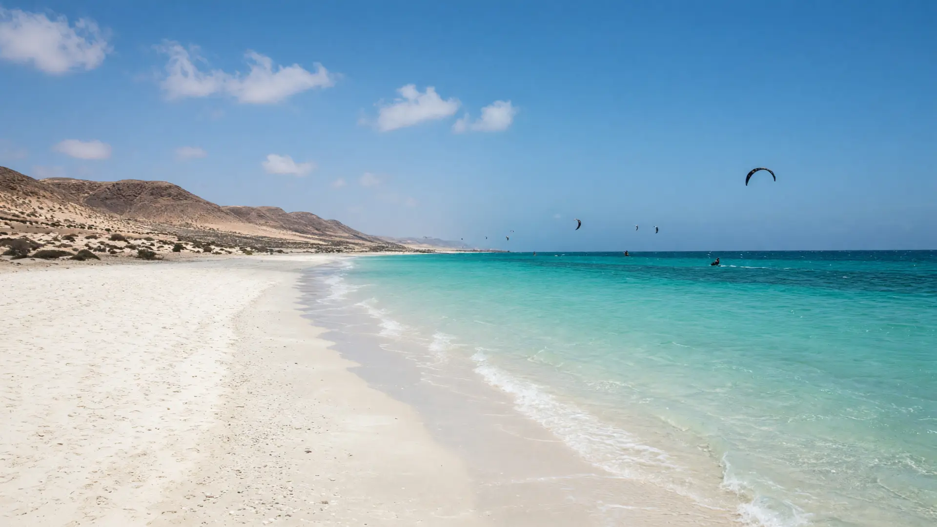 Lang wit zandstrand met turquoise water en kitesurfers op Sal in Kaapverdië