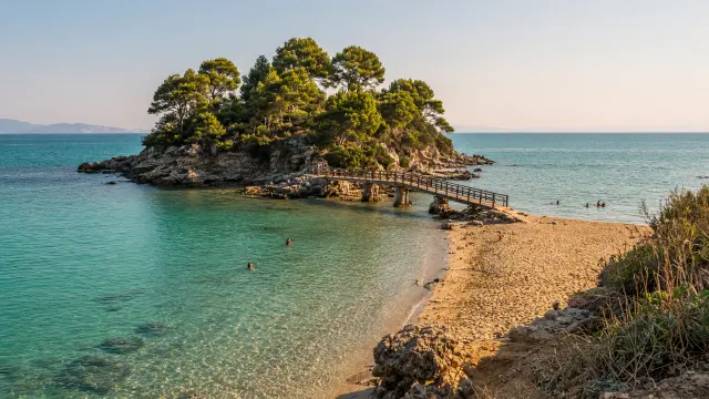 Groen eilandje met een houten voetbrug naar een zandbaai in Agios Sostis op Zakynthos