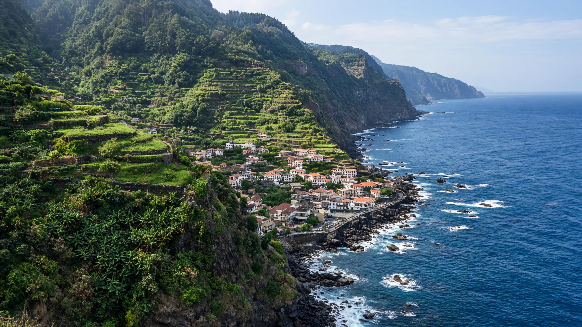 Groene kliffen en een kustplaats met rode daken op Madeira