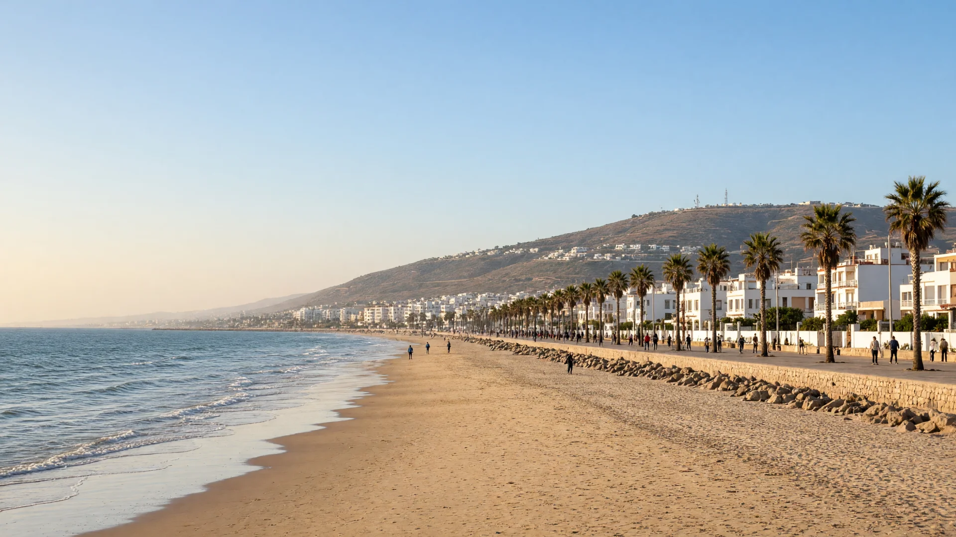 Breed zandstrand met promenade en palmbomen aan de Marokkaanse kust