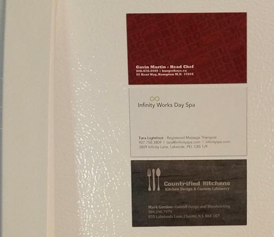 Three business card magnets on a fridge. 