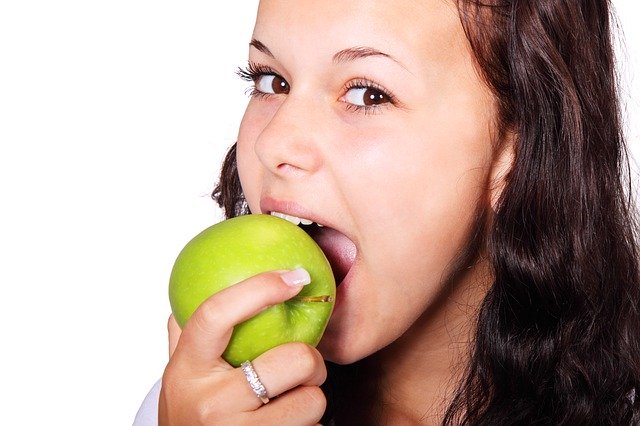 Femme en train de croquer dans une pomme: rôle de la mastication et définition.