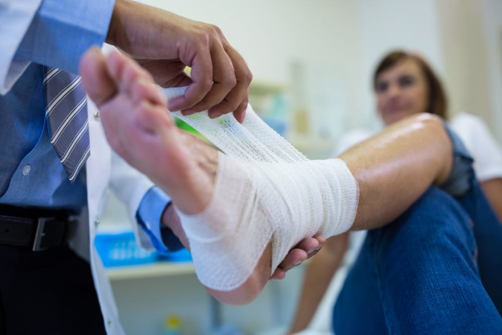 Médecin en train de faire un bandage pour un ulcère de jambe.