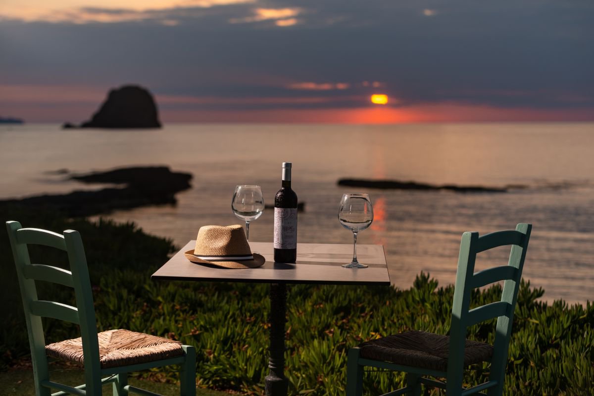 Domus Litus τραπέζι με μπουκάλι κρασί και θέα ηλιοβασίλεμα.