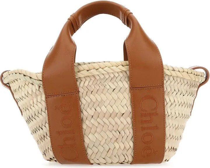 Handbag realized in raffia enriched by logoed calf leather bands.