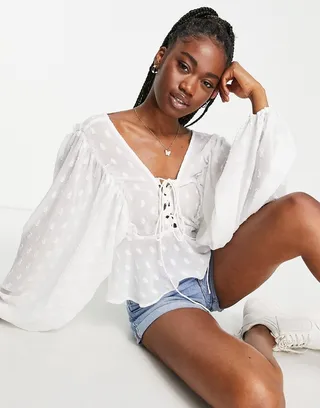 ASOS DESIGN textured long sleeve blouse with lace up front & peplum hem in ivory