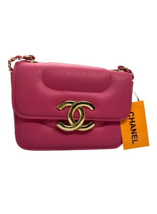 A luxurious women's handbag in fuchsia color with a gold metal handle from Chanel 