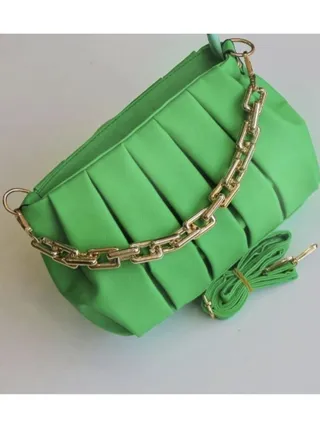A luxurious women's leather bag in mint green color and a golden metal handle 