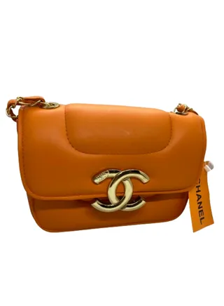 A luxury women's handbag in orange color with a gold metal handle from Chanel 